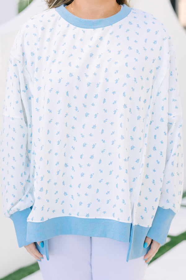 Plus Size white pullover with blue floral print, ribbed trim, and exposed seam details.