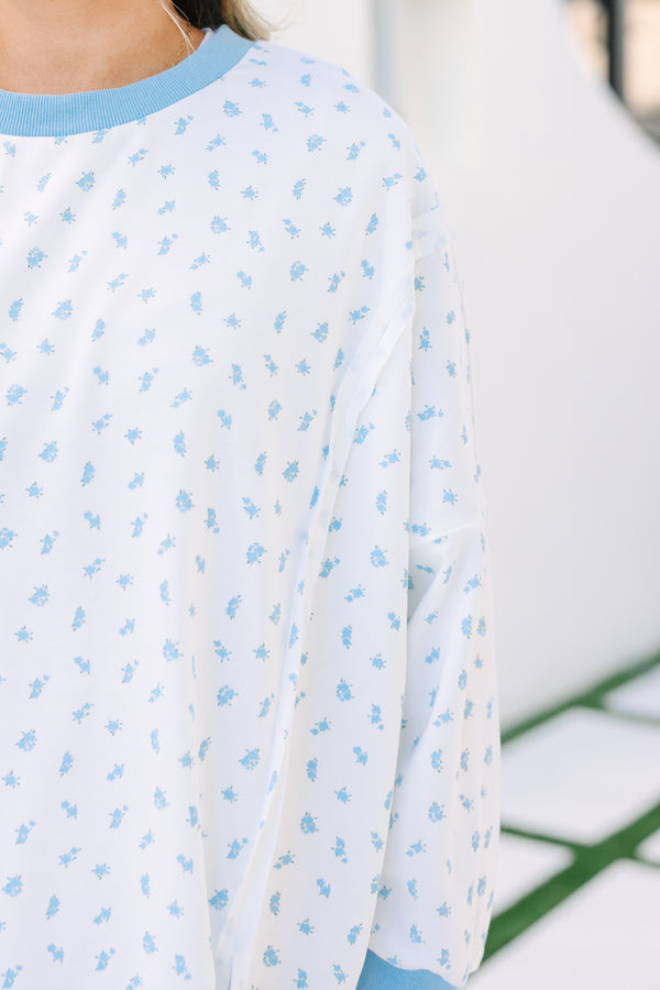 Plus Size white pullover with blue floral print, ribbed trim, and exposed seam details.