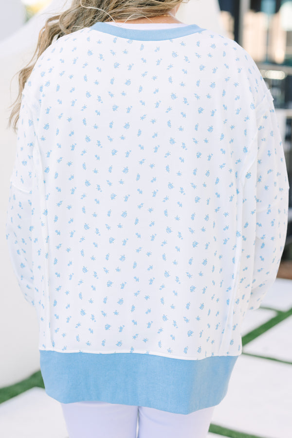 Plus Size white pullover with blue floral print, ribbed trim, and exposed seam details.