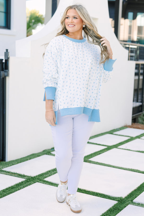 Plus Size white pullover with blue floral print, ribbed trim, and exposed seam details.