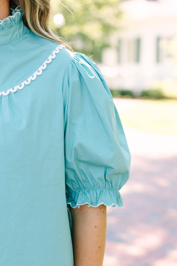 Plus Size green top with a ruffled high neck, white scalloped trim, and puff sleeves.