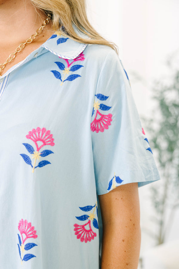 Plus size baby blue shirt dress with magenta floral embroidery, short sleeves, and a flowy fit.