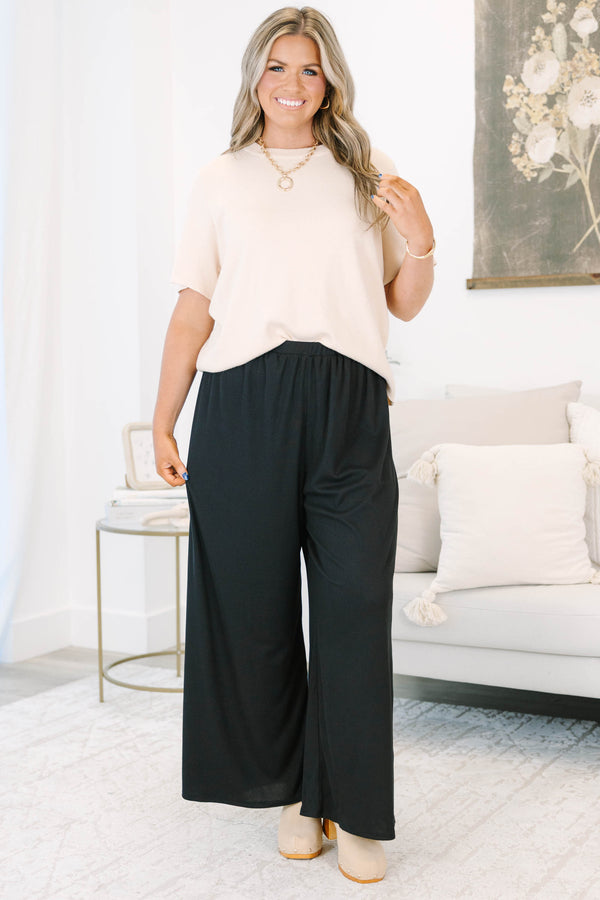 Plus size black flowy palazzo pants with a high-rise elastic waistband and soft ribbed fabric.