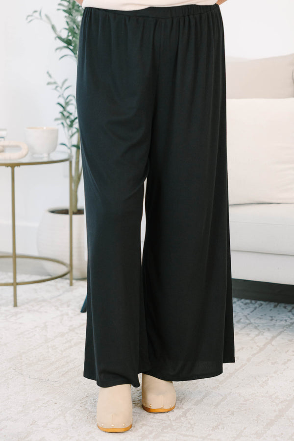 Plus size black flowy palazzo pants with a high-rise elastic waistband and soft ribbed fabric.