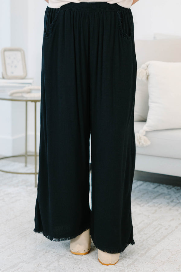 Plus Size black wide-leg pants with an elastic waistband, side pockets, and frayed hem detail.