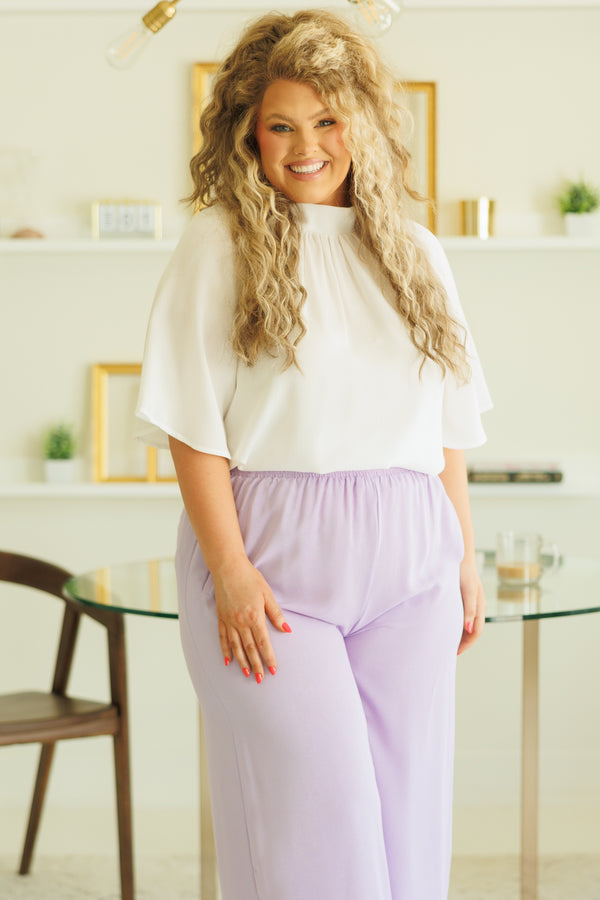 Plus Size white high-neck top with flutter sleeves paired with light purple wide-leg pants.