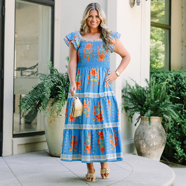 Plus Size blue tiered maxi dress with orange floral print, smocked bodice, and flutter sleeves.
