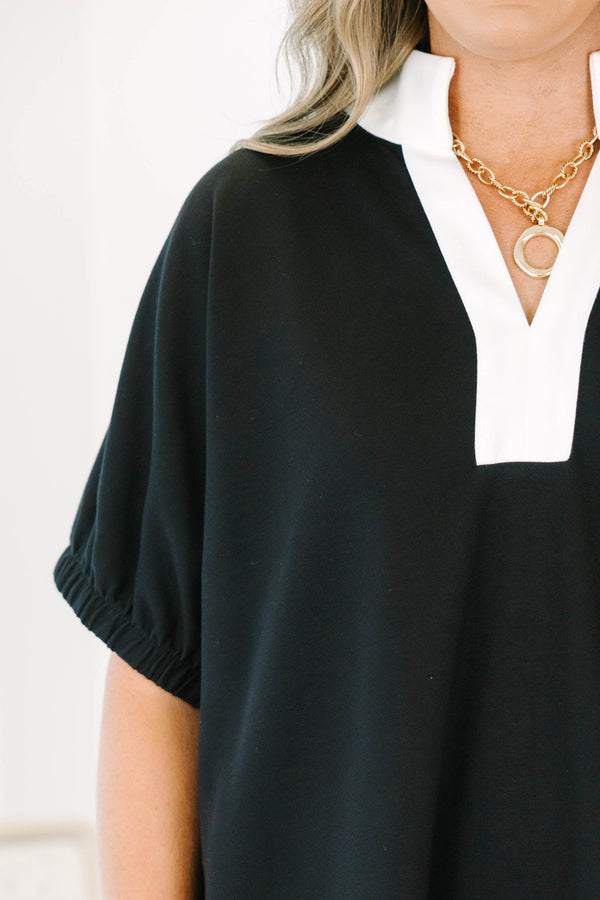 Plus size black top with a white v-neck collar, flowy fit, and short puff sleeves.
