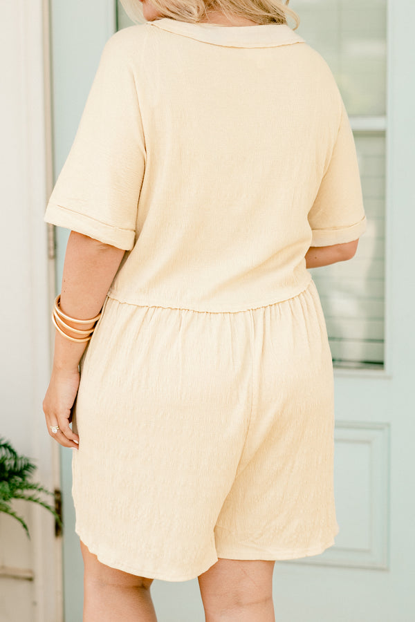 Chic Soul plus size clothing, beige short sleeve romper with five buttons going down the top of the chest and cuffs at the end of the sleeves 
