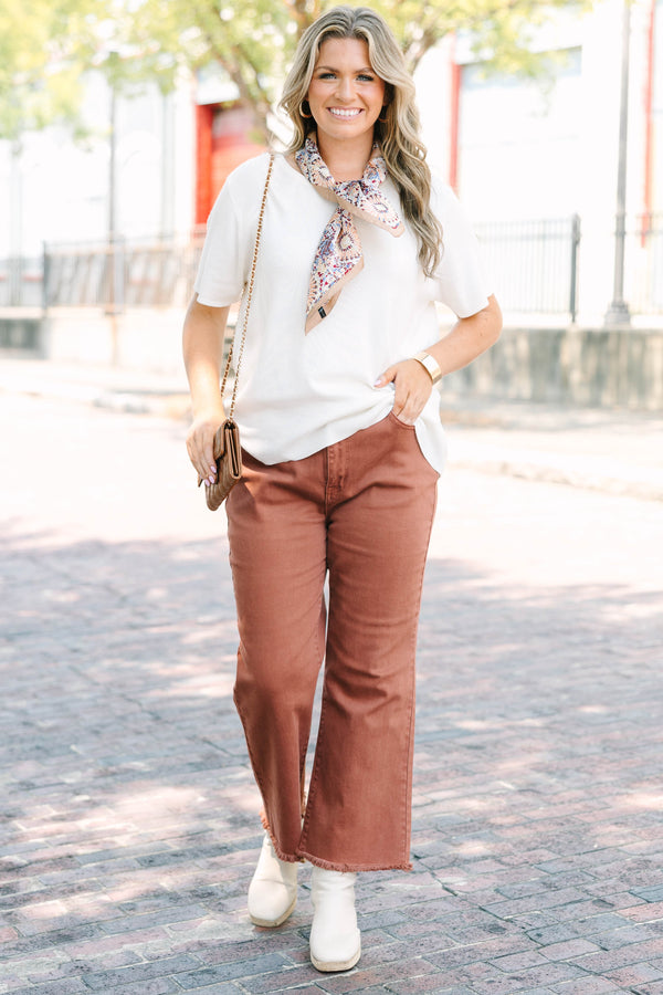 Plus Size dark rust acid-washed high-waisted boot cut jeans with a frayed hem.