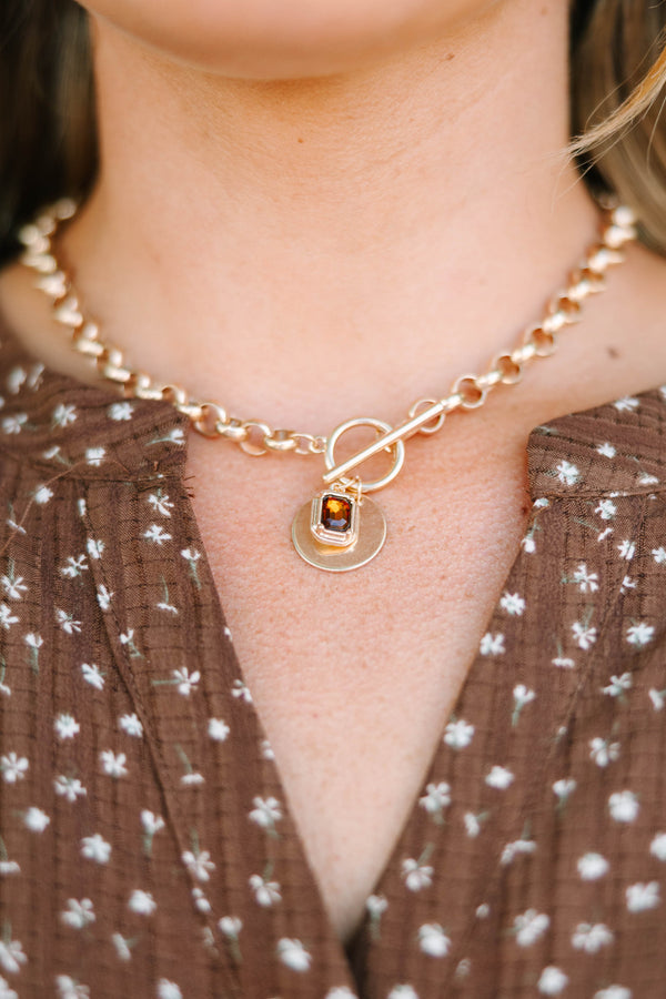 Gold chunky chain necklace with a toggle clasp and amber gemstone pendant on a plus size model.