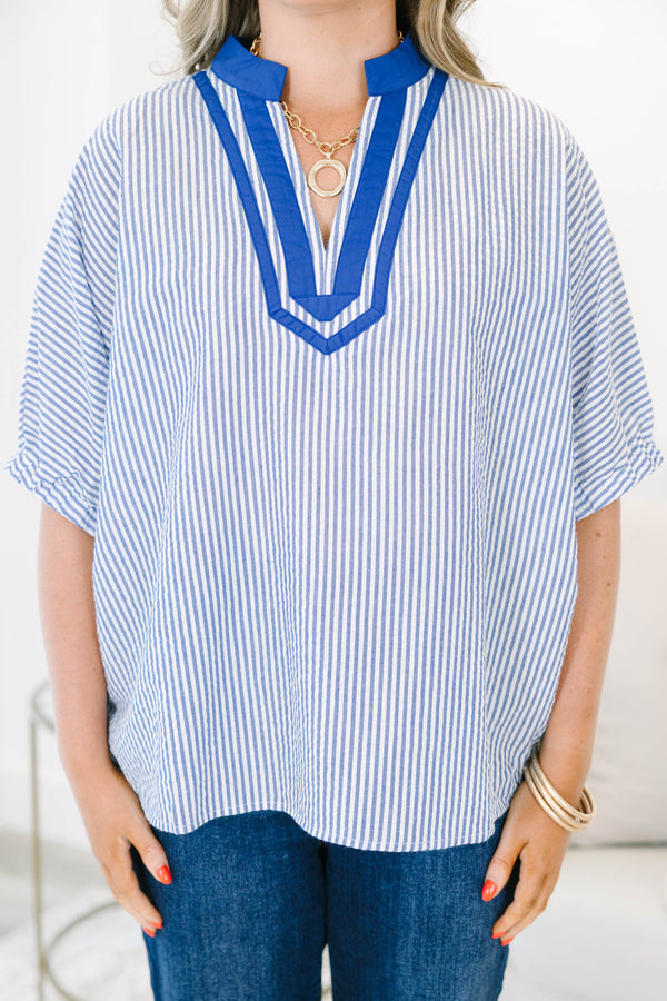 Blue and white vertical striped popover top featuring a bold royal blue contrast V-neck collar trim.