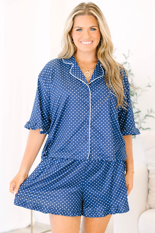 Plus Size navy blue pajama set with white polka dots, button-down top, and ruffled hem shorts.