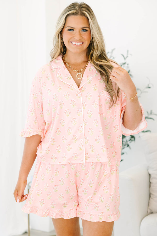 Plus Size pink block print pajama set with short sleeves, button-down top, and ruffled shorts.