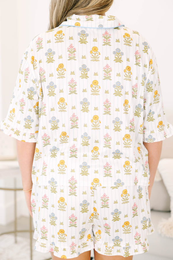 Plus Size white floral pajama set with short sleeves, button-down top, and matching ruffled shorts.
