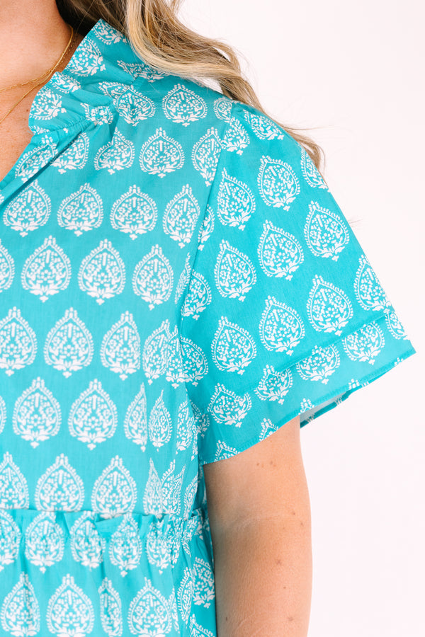 Chic Soul plus size clothing, teal top with short sleeves that have a ruffle flare on the ends of the sleeves as well as a slight v-neckline and an abstract white block pattern throughout 
