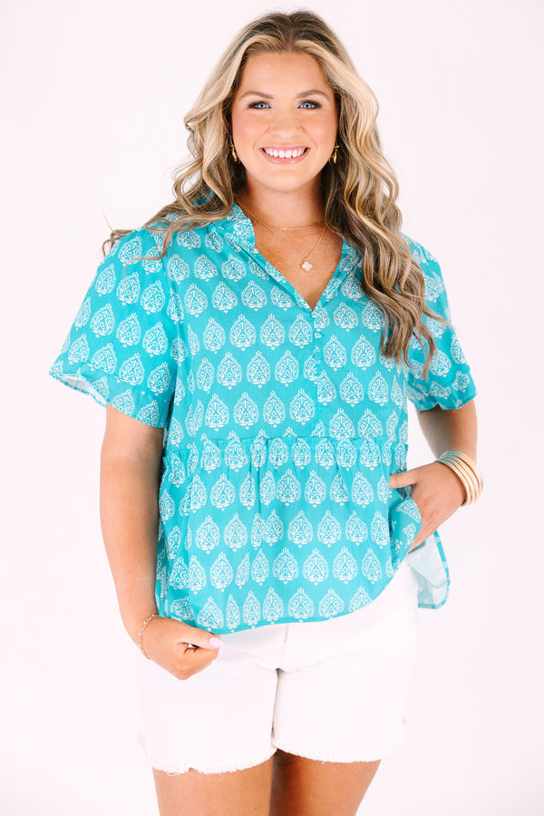 Chic Soul plus size clothing, teal top with short sleeves that have a ruffle flare on the ends of the sleeves as well as a slight v-neckline and an abstract white block pattern throughout 

