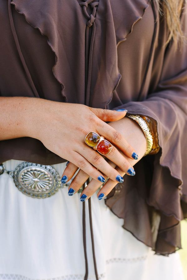 Cowgirl Charm Ring in brown and amber tones on a model with blue nails and western accessories.