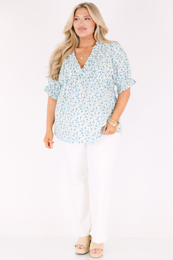 Chic Soul plus size clothing, white top with short sleeves that have a ruffle cuff at the end of the sleeves as well as ruffle detailing going along the v-neckline and under the bust as well as a blue floral pattern 