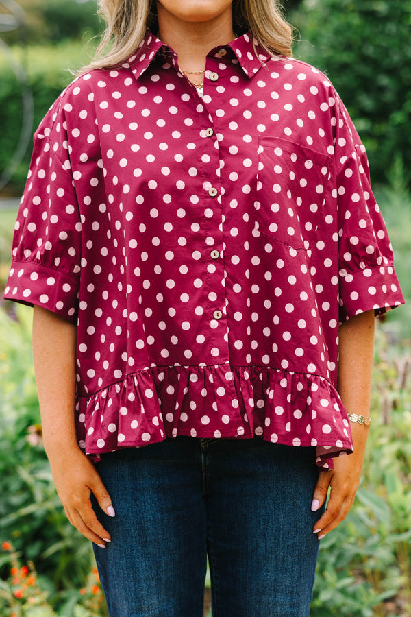 Plus Size wine-colored button-down cotton top with white polka dots, short sleeves, and ruffle hem.