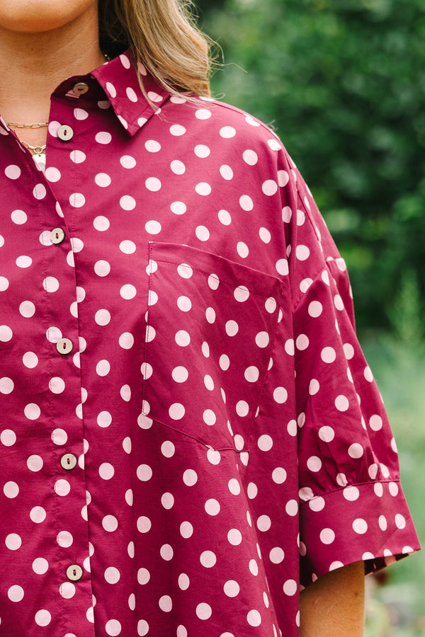 Plus Size wine-colored button-down cotton top with white polka dots, short sleeves, and ruffle hem.