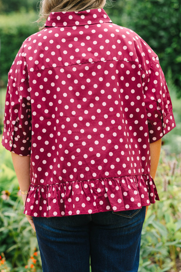 Plus Size wine-colored button-down cotton top with white polka dots, short sleeves, and ruffle hem.