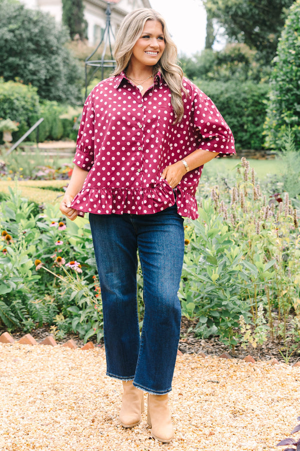 Plus Size wine-colored button-down cotton top with white polka dots, short sleeves, and ruffle hem.