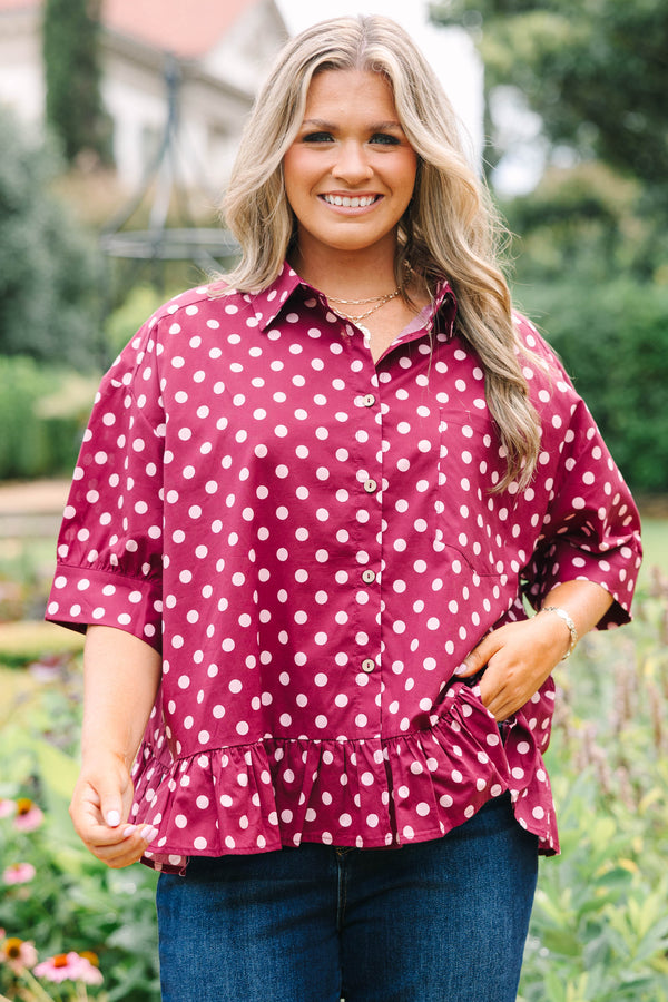 Plus Size wine-colored button-down cotton top with white polka dots, short sleeves, and ruffle hem.