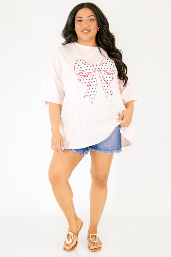 Chic Soul plus size clothing, Cream pink short sleeve graphic tee featuring a white bow graphic centered on the chest, filled with black polka dots and outlined in a darker pink 
