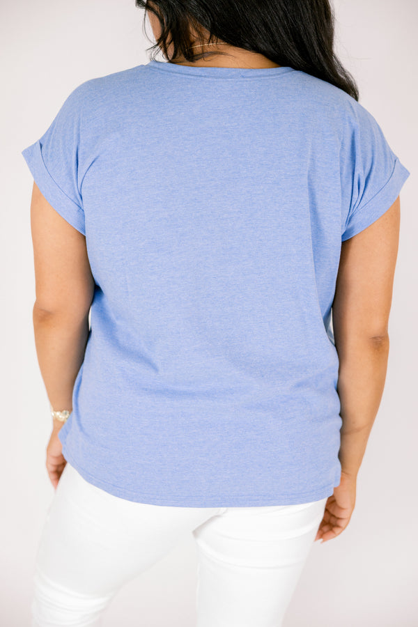 Plus Size heather ocean blue crew neck tee with cuffed short sleeves and white pants.