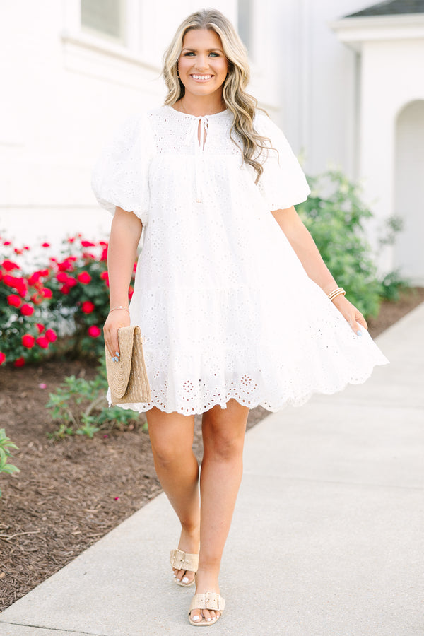 Plus Size white eyelet mini dress with puff sleeves, smocked bodice, and tassel tie neckline.