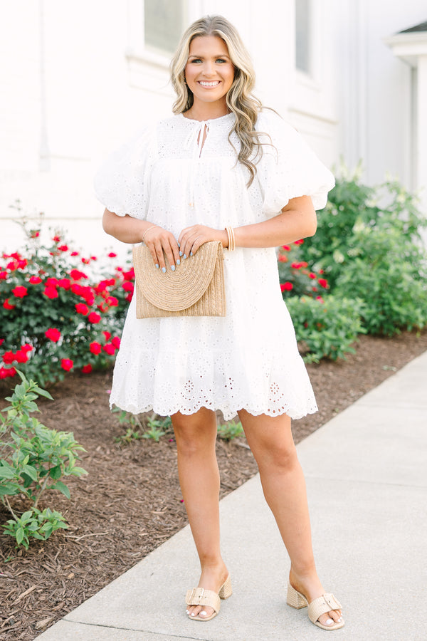 Plus Size white eyelet mini dress with puff sleeves, smocked bodice, and tassel tie neckline.