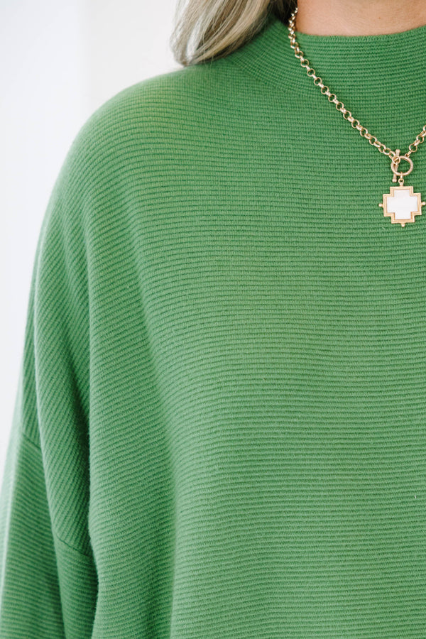 Plus size olive green ribbed sweater with a flowy oversized fit, mock neck, and wide bell sleeves.