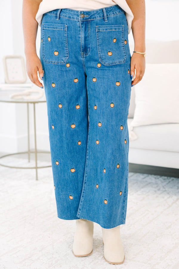 Plus size wide leg blue denim jeans with all-over pumpkin embroidery and a raw hem.
