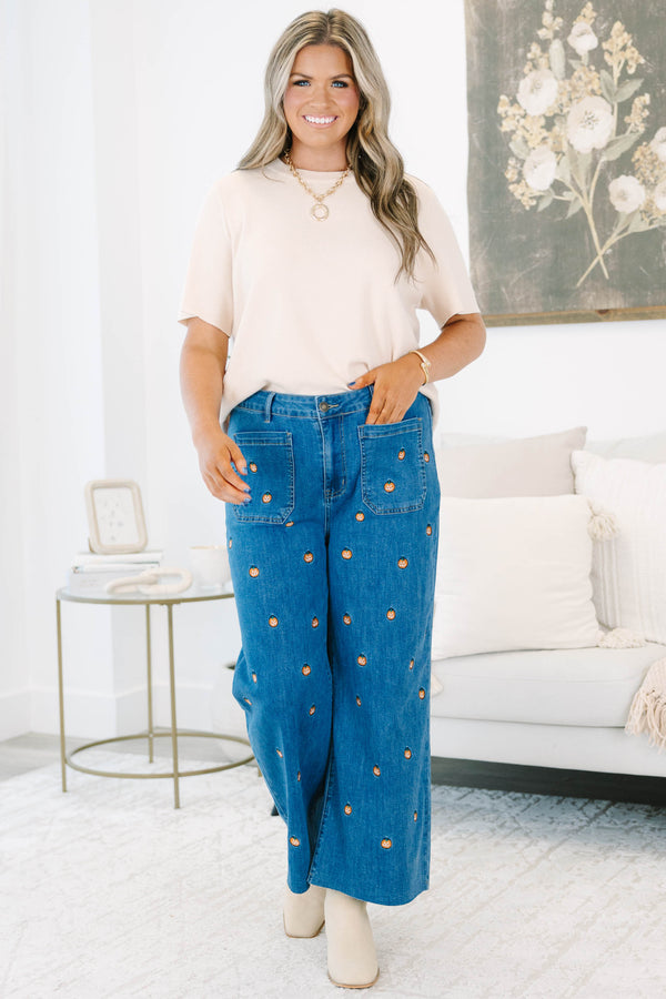 Plus size wide leg blue denim jeans with all-over pumpkin embroidery and a raw hem.