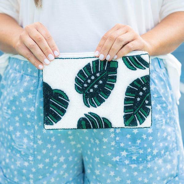 Plus Size white beaded clutch with green tropical leaf patterns and a top zipper closure.