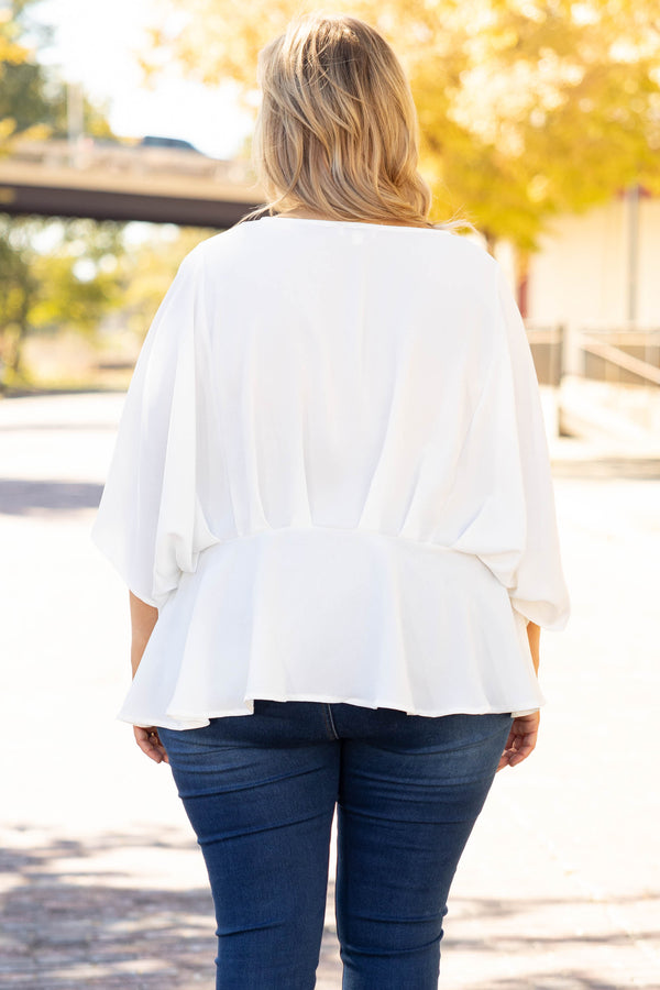 Plus Size ivory flowy blouse with batwing sleeves and a v-neckline paired with dark wash jeans.