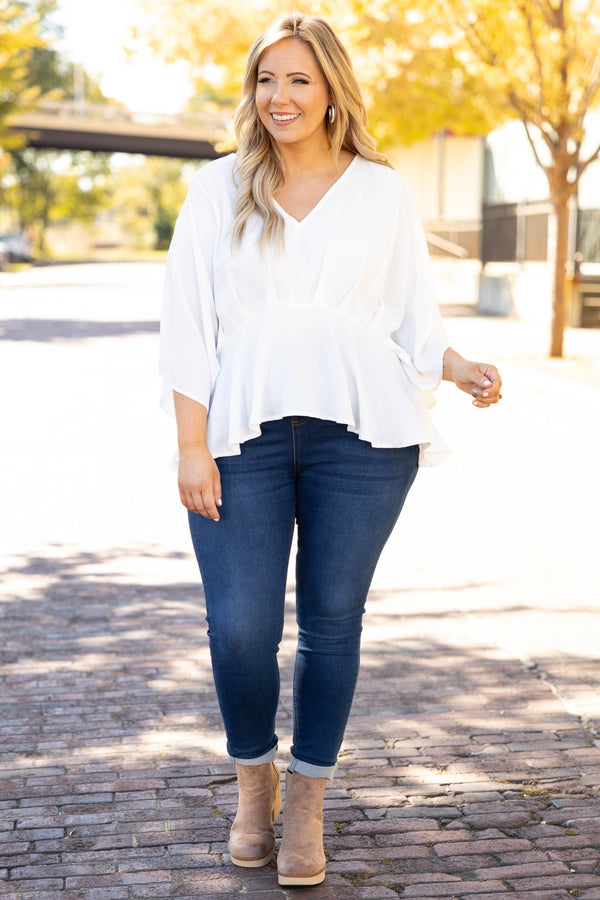 Plus Size ivory flowy blouse with batwing sleeves and a v-neckline paired with dark wash jeans.