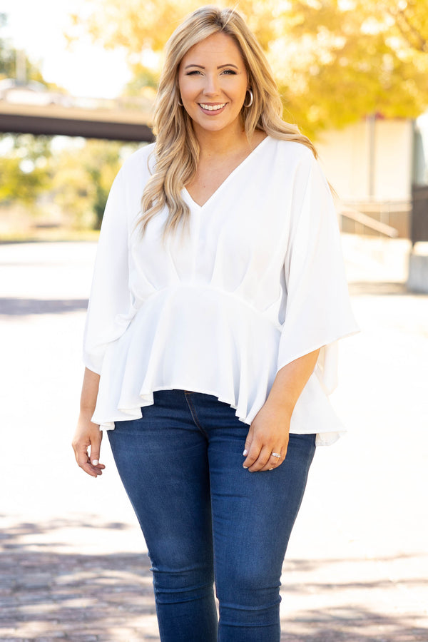 Plus Size ivory flowy blouse with batwing sleeves and a v-neckline paired with dark wash jeans.