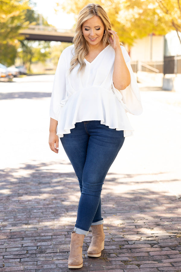 Plus Size ivory flowy blouse with batwing sleeves and a v-neckline paired with dark wash jeans.