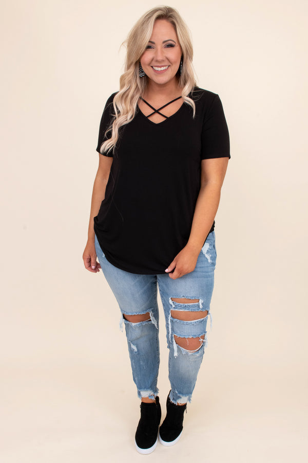 Plus Size black short sleeve top with a criss-cross V-neckline and distressed light wash jeans.