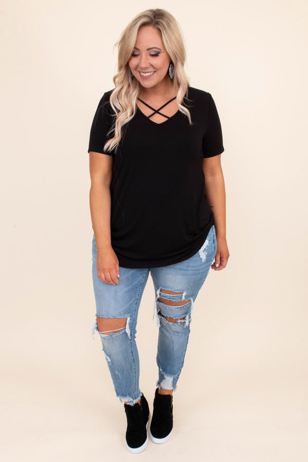 Plus Size black short sleeve top with a criss-cross V-neckline and distressed light wash jeans.