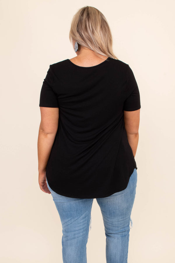 Plus Size black short sleeve top with a criss-cross V-neckline and distressed light wash jeans.