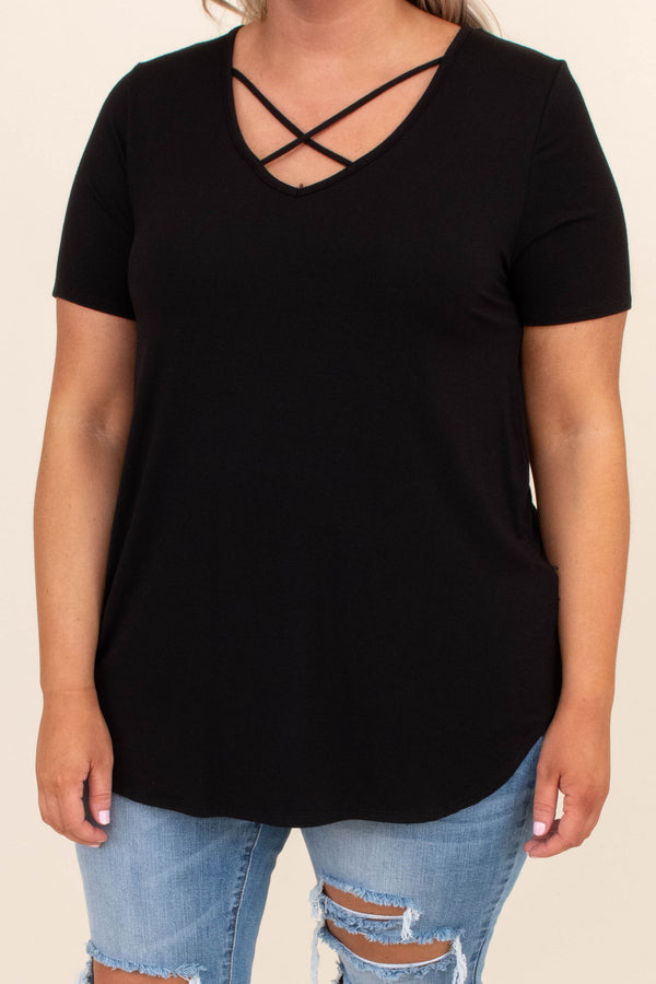 Plus Size black short sleeve top with a criss-cross V-neckline and distressed light wash jeans.