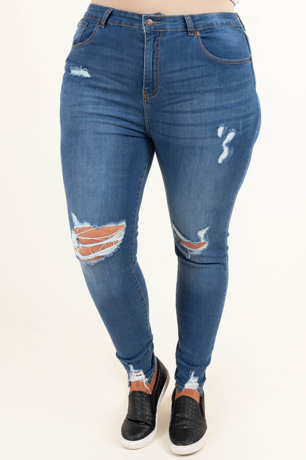 Plus Size medium wash distressed skinny jeans with ripped knees and frayed hems.