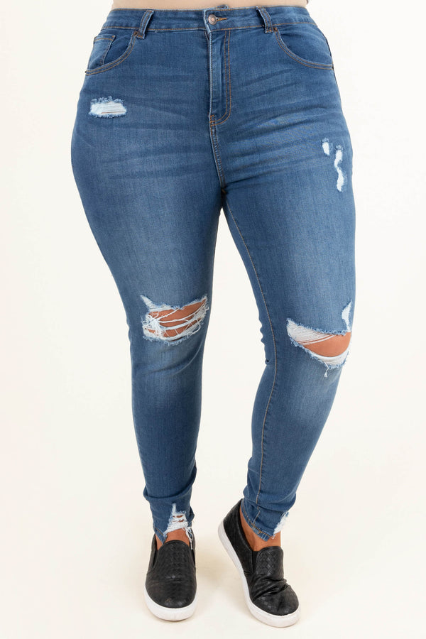 Plus Size medium wash distressed skinny jeans with ripped knees and frayed hems.