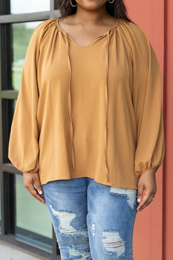 Plus Size toffee-colored v-neck top with bubble sleeves and distressed blue denim jeans.