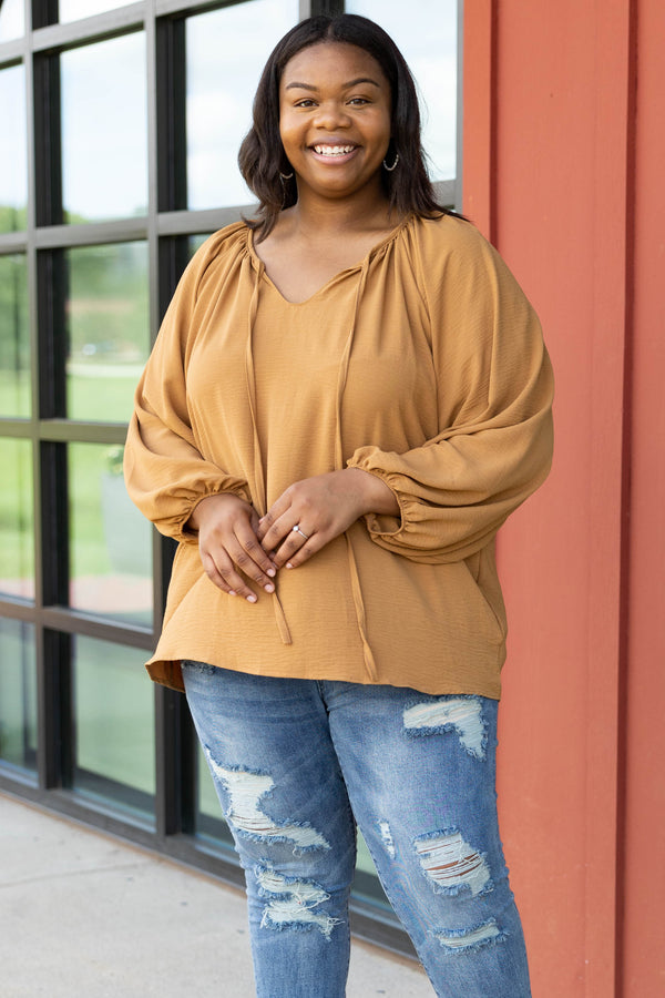 Plus Size toffee-colored v-neck top with bubble sleeves and distressed blue denim jeans.
