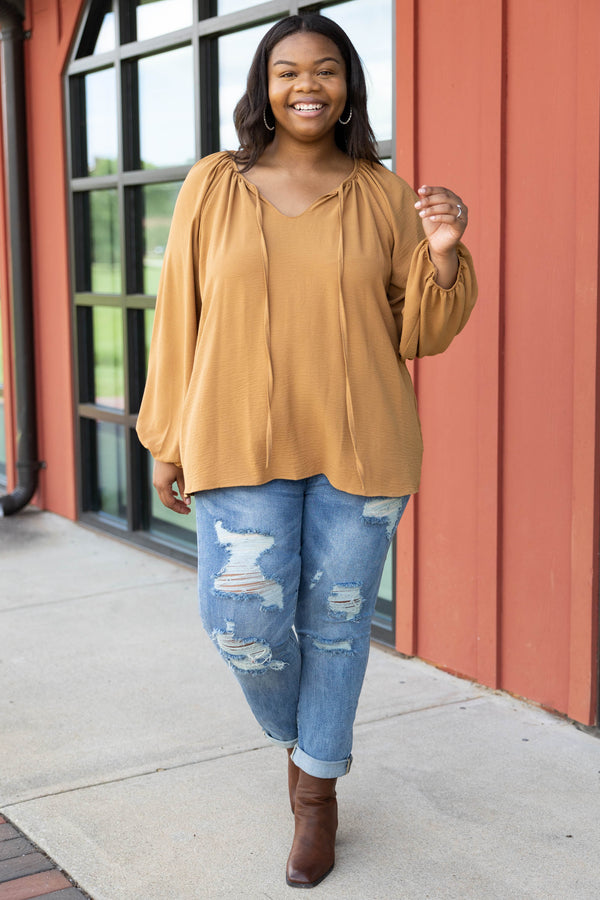 Plus Size toffee-colored v-neck top with bubble sleeves and distressed blue denim jeans.
