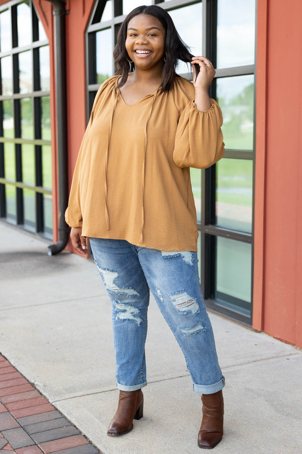 Plus Size toffee-colored v-neck top with bubble sleeves and distressed blue denim jeans.